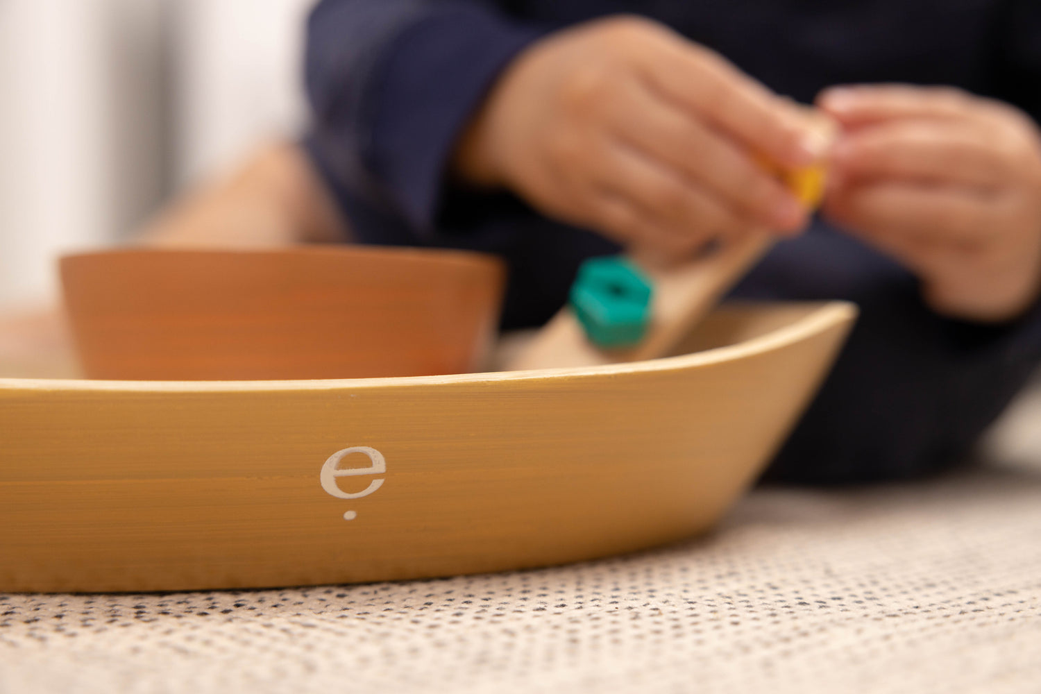 close up image of Montessori tray with bowl and child's hands in the background