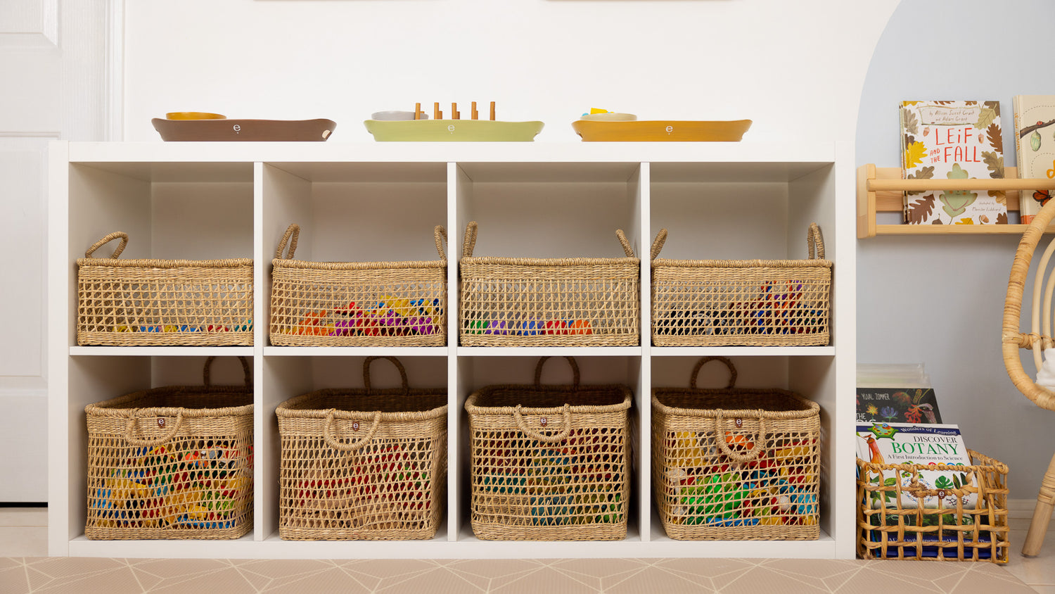 Calm and orderly Montessori play space with natural baskets and trays on an IKEA Kallax shelf