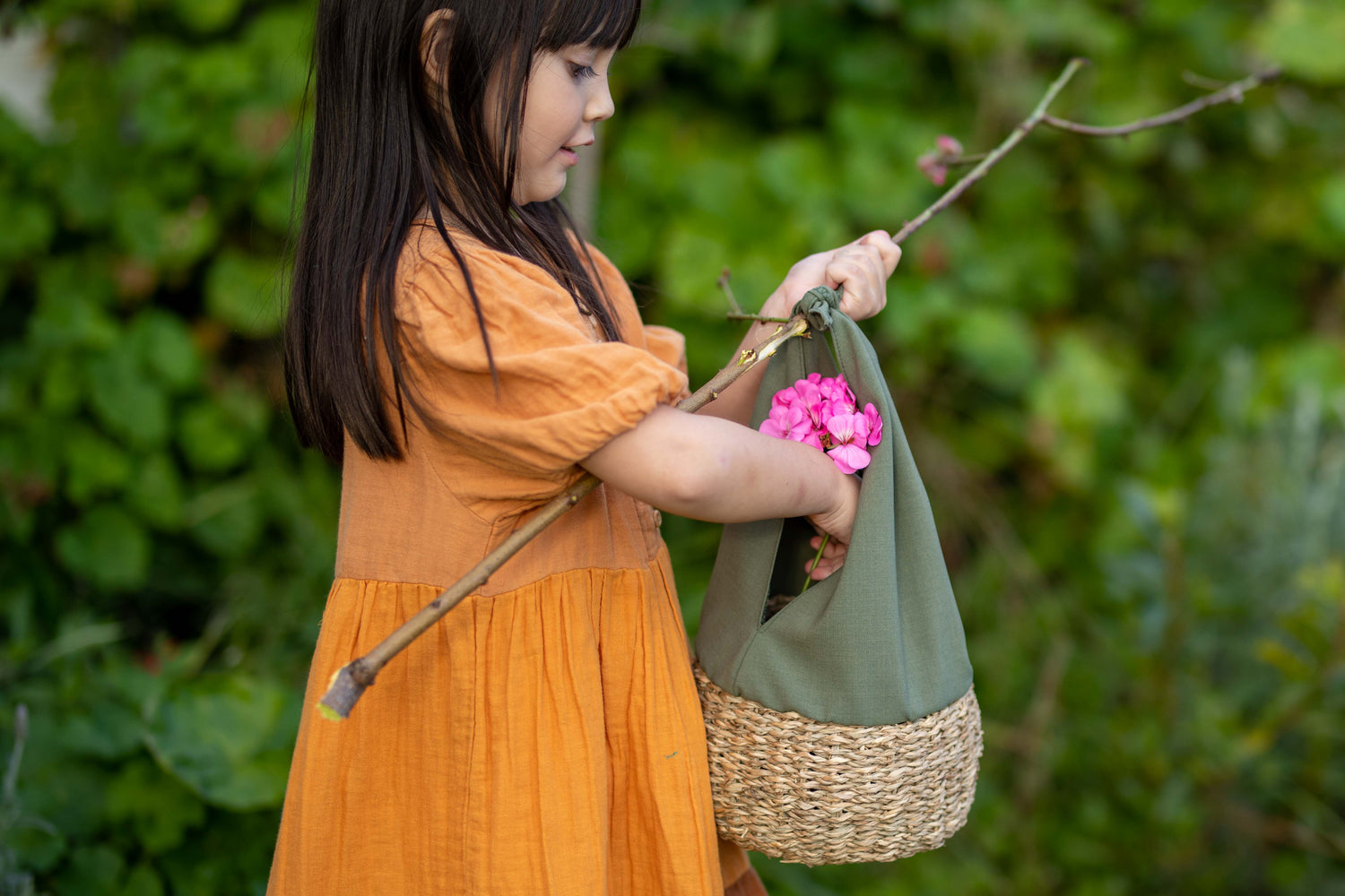 Child placing flower inside a child sized basket while outdoors