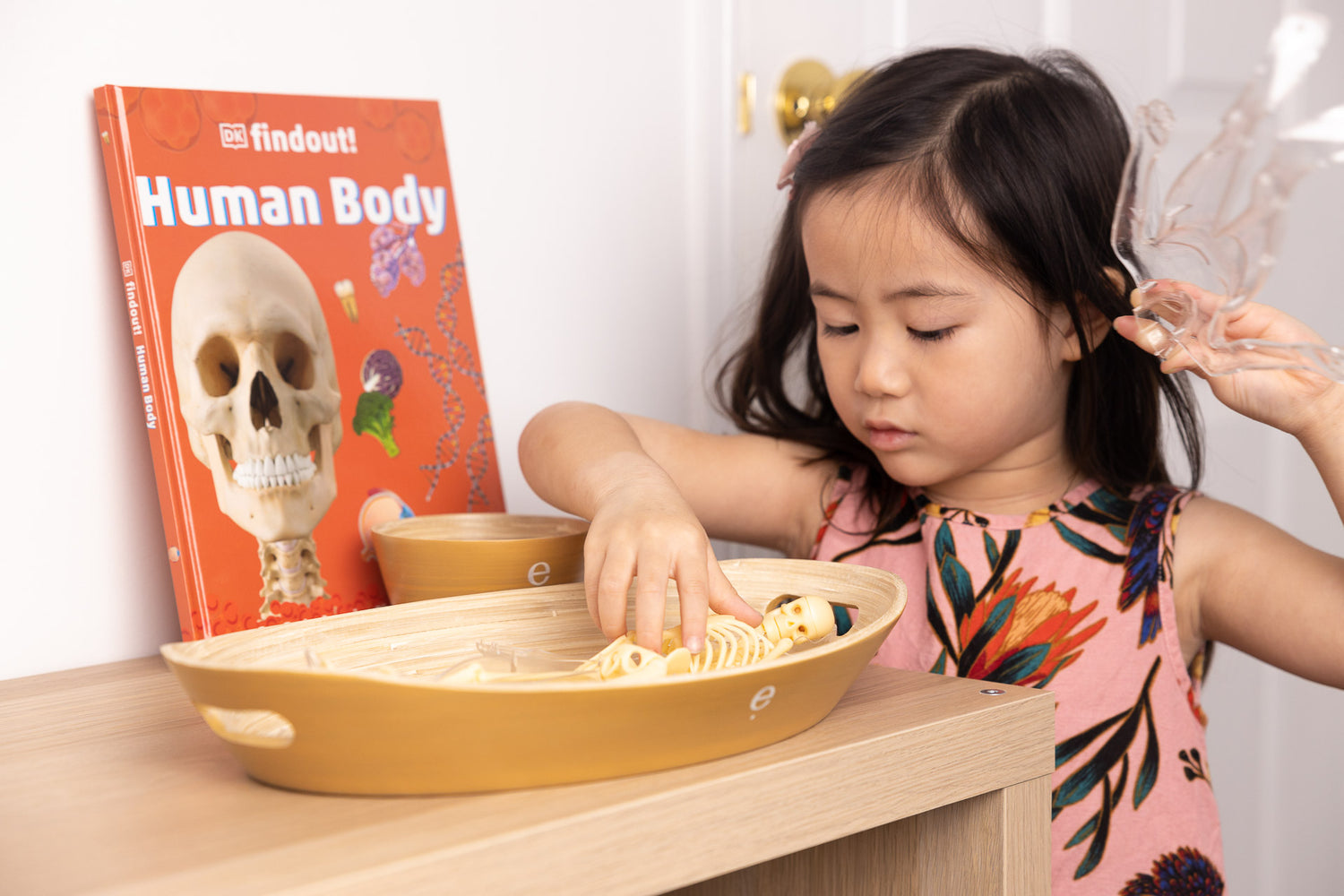 Child reaching into large natural spun bamboo oval tray to engage with Montessori activity