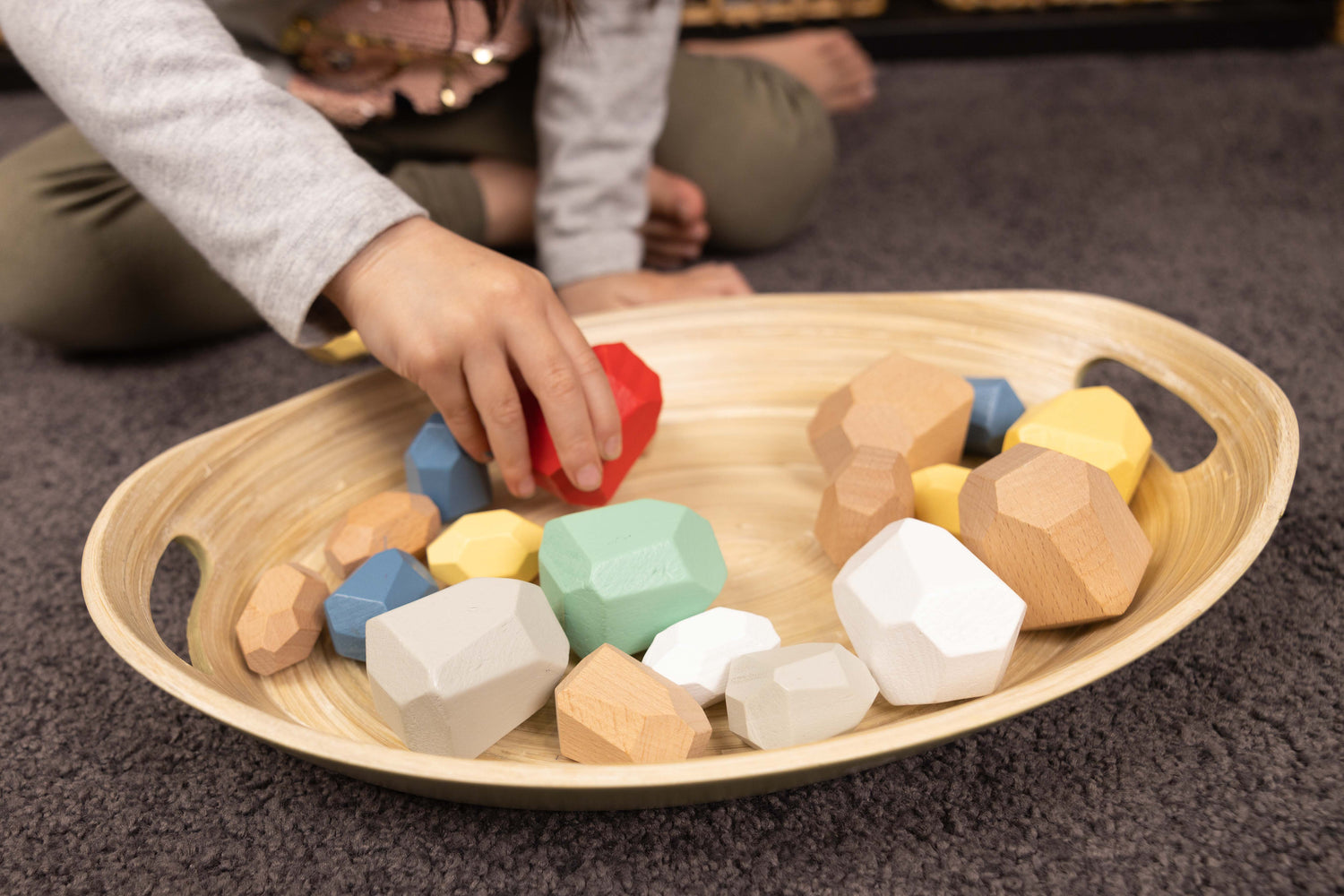 child's hand engaging with activity inside Montessori tray