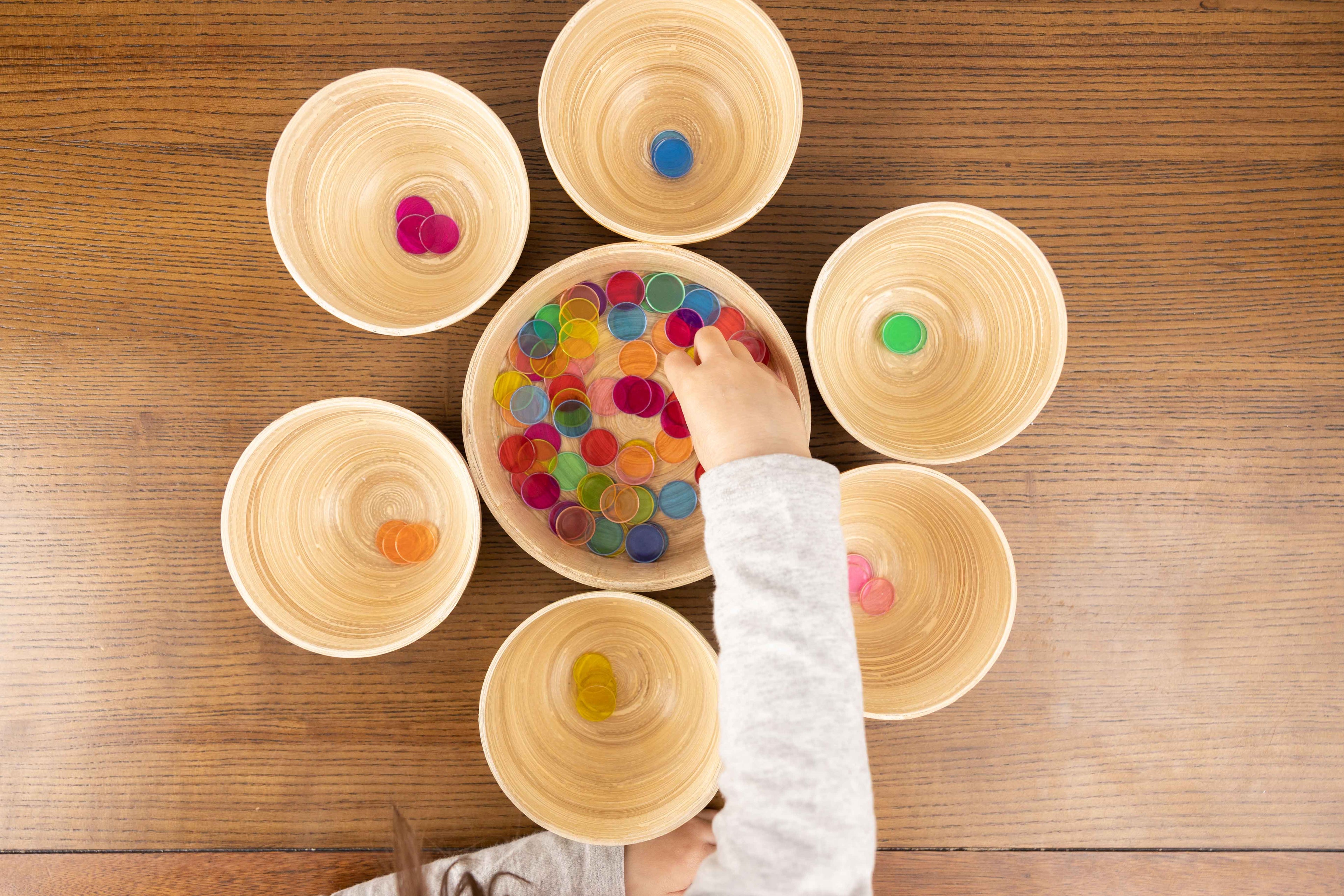 child's hand engaging with colour sorting activity using Montessori sorting bowl set