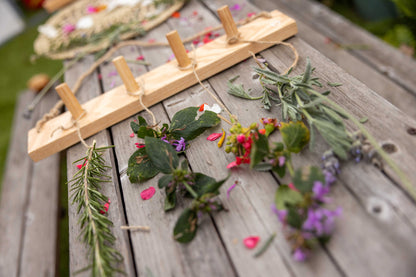 artistic photo of wall hanger with fresh flowers and herbs tied to it